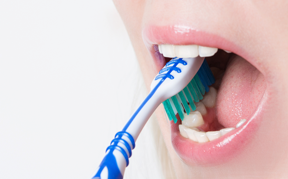 Close up of toothbrush in woman’s mouth preventing tooth decay